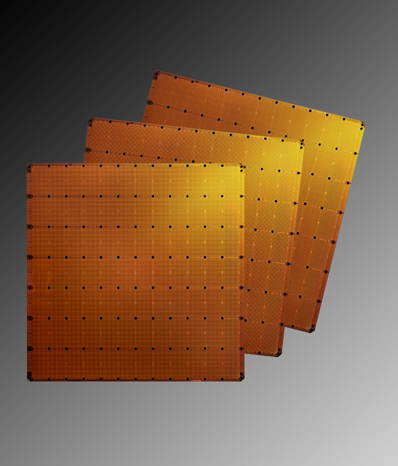Three golden WSE-3 wafer-scale processors, each a full 300mm silicon wafer patterned with dies